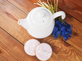 Obraz na płótnie Canvas Teapot and gingerbread with muscari top view. Beautiful morning, breakfast, tea party celebration, wooden table, background concept
