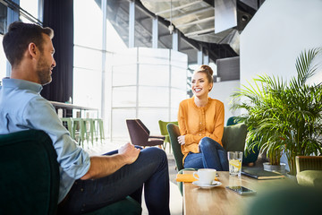 Cheerful coworkers chatting and waiting for lunch while on break from work in cafeteria