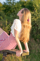 ein blondes Mädchen  hängt Ihre langen Haare nach hinten in die Abendsonne