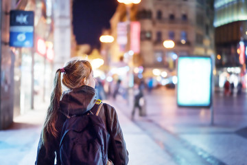 Back view of girl walking on city street at night, Prague