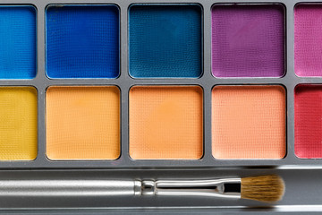 professional cosmetics. Palette of multicolored eye shadow and makeup brush, top view