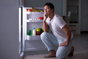 Man at the fridge eating at night
