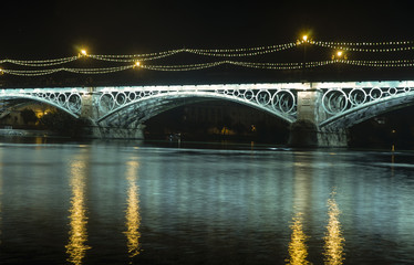 Iluminación nocturna del hermoso puente de Triana en la ciudad de Sevilla, España