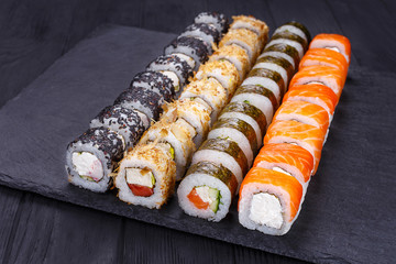 Delicious multicolored uramaki sushi rolls set, great assortment of tasty snacks, decorated with sesame. Restaurant menu, Japanese food art
