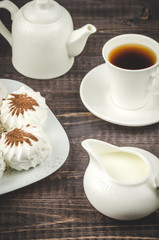 Fototapeta na wymiar creamer, cup of coffee and marshmallows/creamer, cup of coffee, teapot and dessert on a dark table