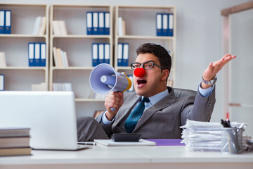 Clown businessman angry in the office with a megaphone