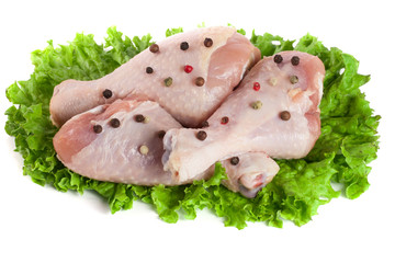 Three raw chicken drumsticks with lettuce leaf isolated on white background