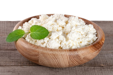 Cottage cheese in a wooden bowl on board with white background