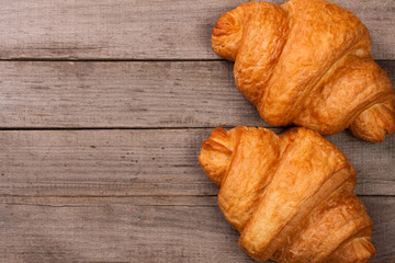 two croissants on old wooden background with copy space for your text. Top view