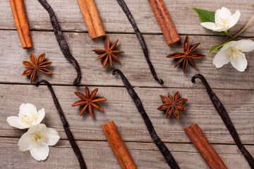 Vanilla sticks and cinnamon with anise and flower on a old wooden background