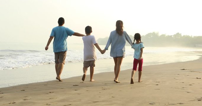 Happy family walking on the tropical coast while holding hands together, shot in 4k resolution