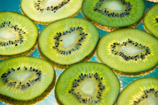 Green kiwi fruit slices on lighted glass