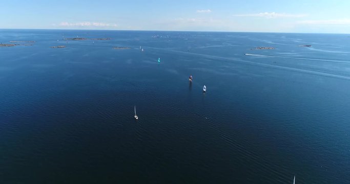 Yachts on baltic sea, Cinema 4k aerial tilt up view above the baltic sea and towards a group of colorful sailboats, out on the turquoise sea, on hango regatta day, in the finnish archipelago
