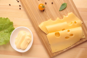 Maasdam cheese sauce on a board and a grater