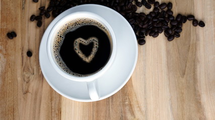 Hearts and Love of coffee. A cup of Americano or espresso on a wood table with roasting beans. Aroma and flavor beverage. Morning breakfast with fresh espresso coffee.