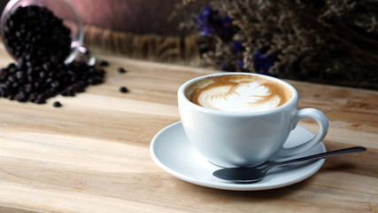 Latte art and cappuccino on the table with roasting coffee beans. Beverage and breakfast or food and drink menu with hot coffee at the cafe shop.