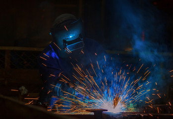 Industrial worker is welding assembly automotive part in car factory