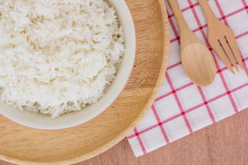 closed up of bowl full of rice in plate and spoon on wooden table