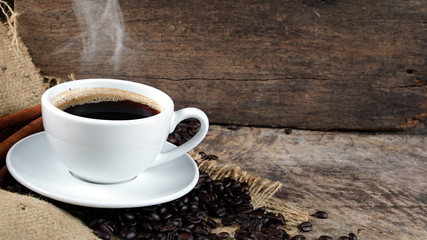 Espresso or americano coffee. A cup of coffee on the wood table with dark roasted coffee beans.