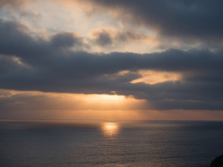 Obraz premium Beams of sunlight show through a cloudy sky onto the ocean