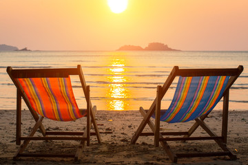 Couple of sun loungers on the beach during sunset.