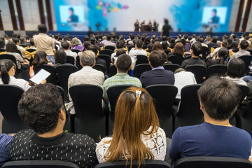 Speakers on the stage with Rear view of Audience in the conference hall or seminar meeting, business and education about investment concept