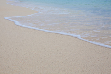 Abstract background of sandy beach with soft waves.