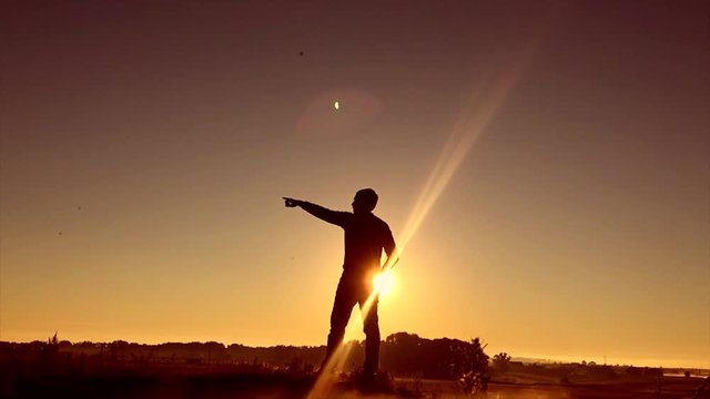Man travel silhouette. Man shows his hand in the distance standing on a mountain silhouette sunrise sunlight
