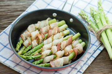 Grilled green asparagus wrapped with bacon in pan.