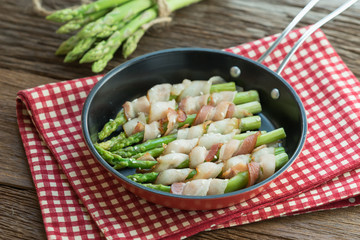 Grilled green asparagus wrapped with bacon in pan.