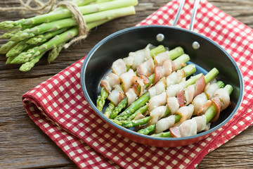 Grilled green asparagus wrapped with bacon in pan.