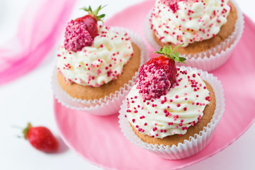 Vanilla cupcakes decorated strawberries on a pink cake stand