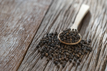 Black pepper in wooden spoon.