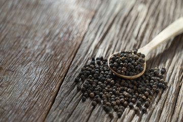Black pepper in wooden spoon.