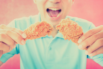 A man with opening mouth about to eat deep fried chicken legs or drumsticks