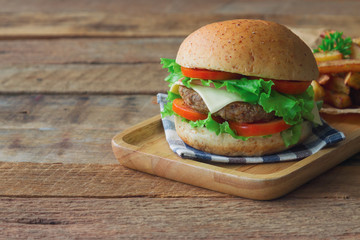 Homemade hamburger on plaid napkin with french fries. Delicious sandwich hamburger with meat or pork ham cheese and fresh vegetable. Hamburger or sandwich is the popular fast food for brunch or lunch.