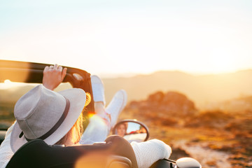 A young woman enjoys a sunset from a convertible