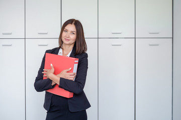 Happy young businesswoman holding a red binder And smiling