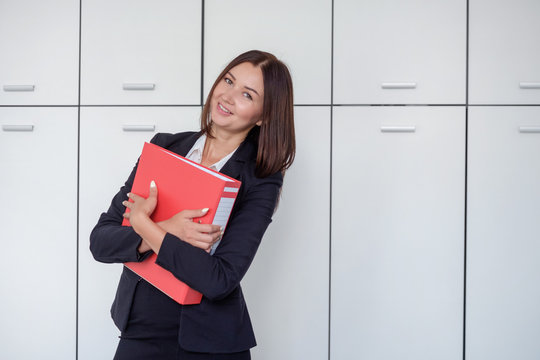 Happy young businesswoman holding a red binder And smiling