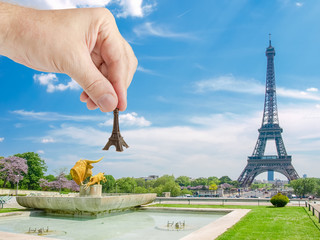 Eiffel Tower model in man's hand against Eiffel Tower