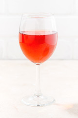 glass of cold red wine on white wooden background