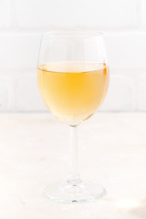 glass of cold white wine on white wooden background