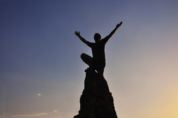 Man raised hand on top of the mountain to celebrate success. Men on the top of the steep rock 