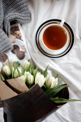 Top view of a cup of tea and white tulips