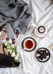 A bouquet of white tulips, a cup of tea and a teapot. view from above