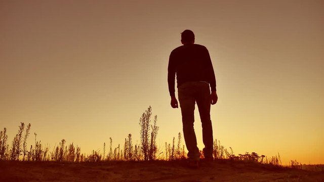 man silhouette. Man walking on summer sunset meadow. man sunset travel slow motion video