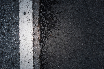 A dark asphalt pavement texture with aged and weathered vertical traffic sign painted with white color