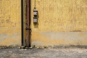Texture of old yellow vintage wall of industrial factory with rusted iron pole and electric cable