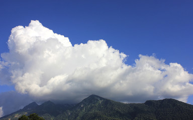 Obraz premium Mountain landscape. Green mountain peaks against blue sky and white clouds.