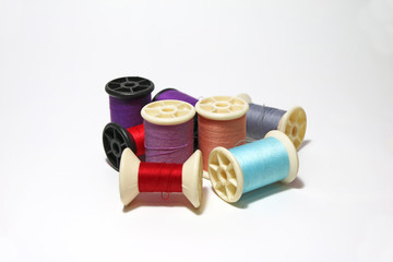 Heap of colorful thread in the thread roll on white background. the color of thread are blue, red, gray, orange, pink, violet.